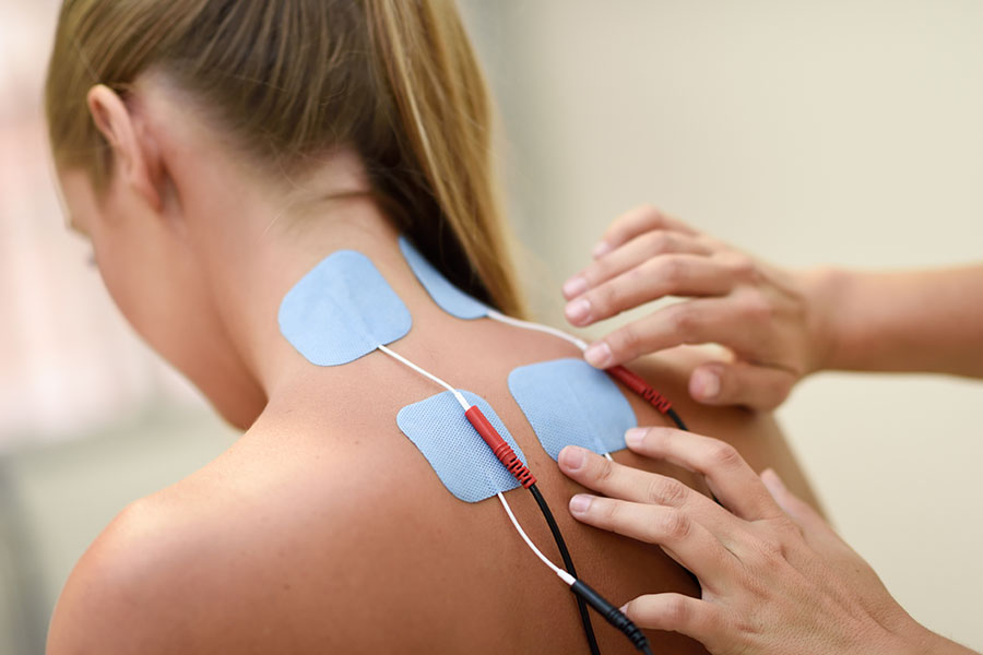 Electro stimulation in physical therapy to a young woman. Medical check at the shoulder in a physiotherapy center.